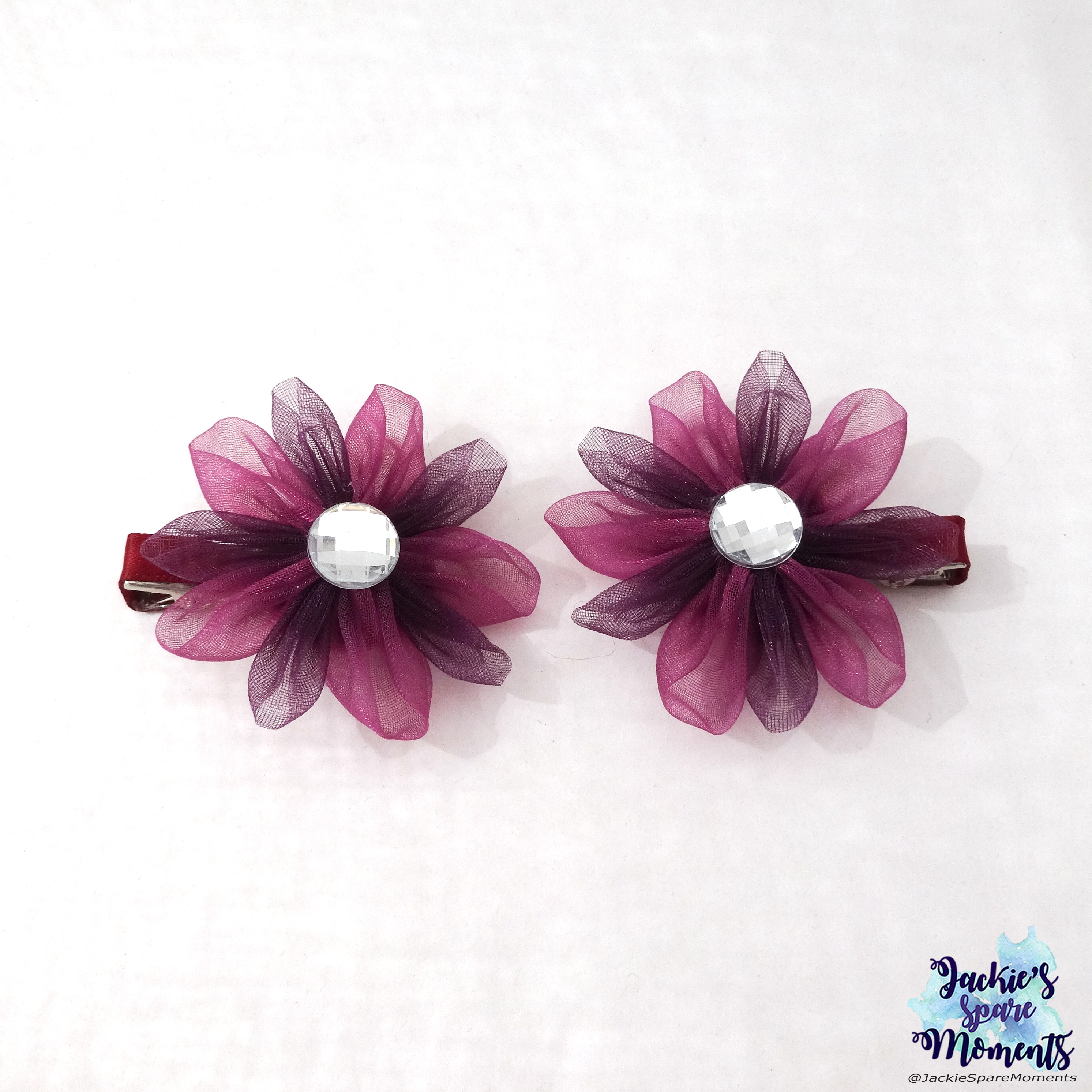 A pair of flower hair bows in autumnal eggplant hues.